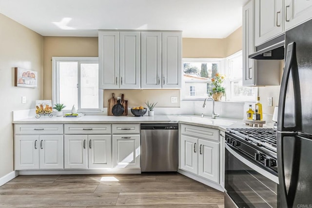 kitchen with white cabinetry, sink, hardwood / wood-style floors, and black appliances