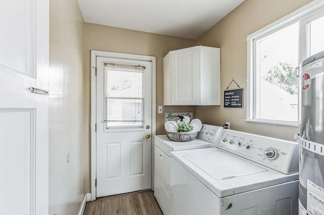 laundry room with separate washer and dryer, light hardwood / wood-style floors, cabinets, and water heater