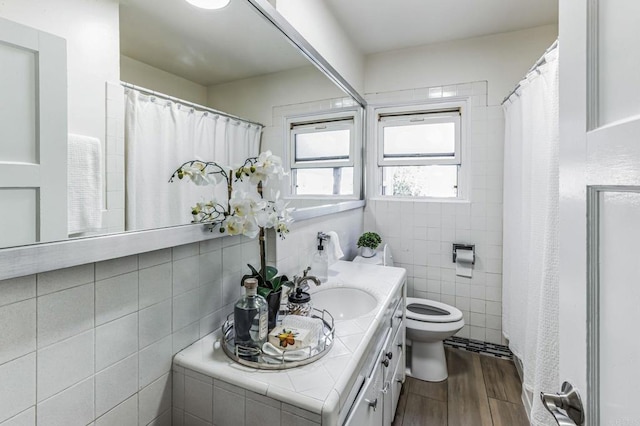 bathroom with vanity, toilet, hardwood / wood-style floors, and tile walls