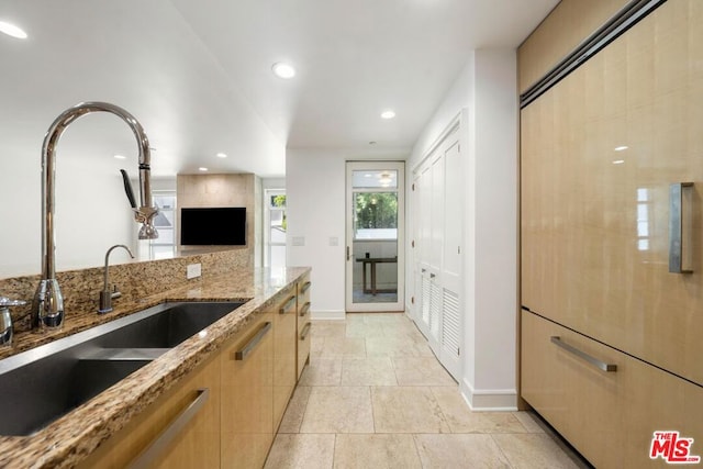 kitchen with sink, light brown cabinets, and light stone countertops