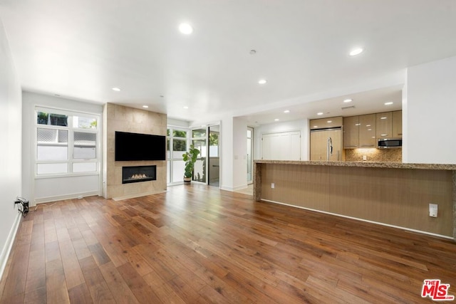 unfurnished living room with a healthy amount of sunlight, dark wood-type flooring, and a fireplace