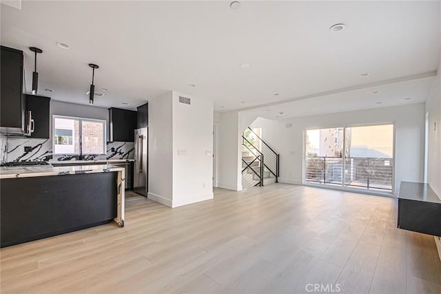 kitchen with high end fridge, decorative light fixtures, light hardwood / wood-style flooring, and tasteful backsplash