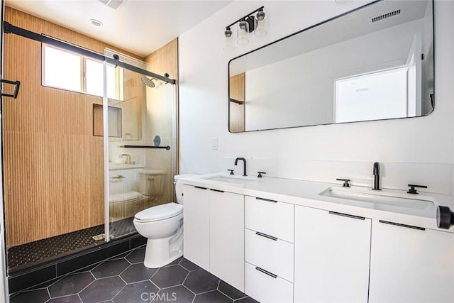 bathroom featuring tile patterned flooring, vanity, a shower with shower door, and toilet