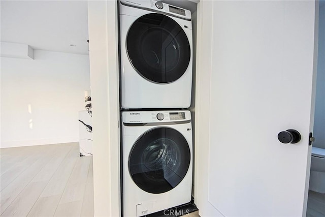 washroom featuring stacked washer and dryer and wood-type flooring