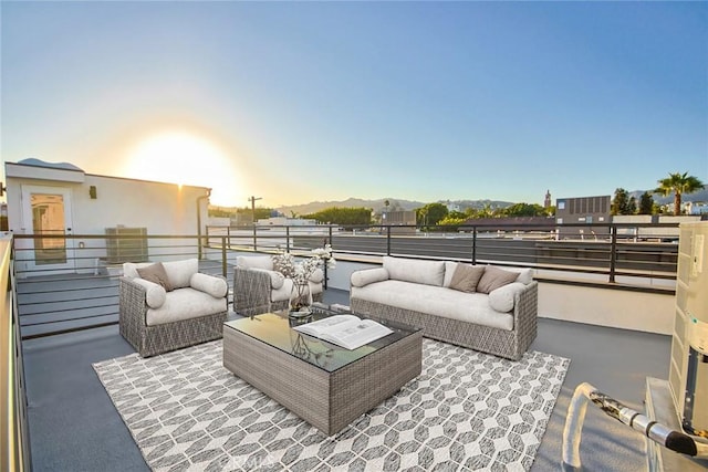 patio terrace at dusk with a balcony, outdoor lounge area, and a mountain view