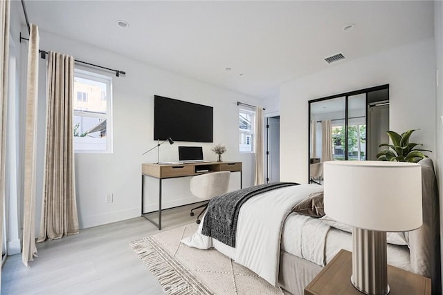 bedroom featuring multiple windows and light hardwood / wood-style flooring