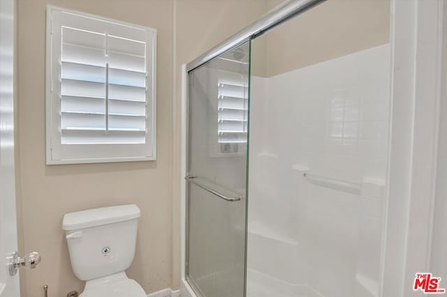 bathroom with a healthy amount of sunlight, a shower with shower door, and toilet