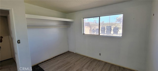 interior space featuring vaulted ceiling, a closet, hardwood / wood-style floors, and a textured ceiling