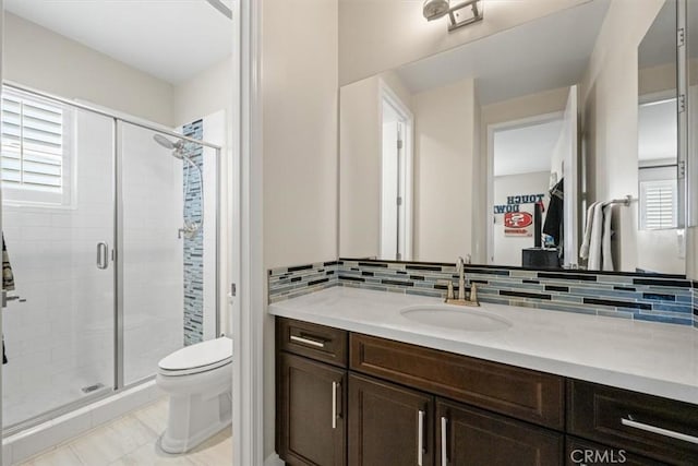 bathroom with backsplash, a wealth of natural light, vanity, and toilet