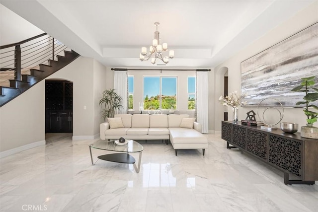 living room with a tray ceiling and a chandelier