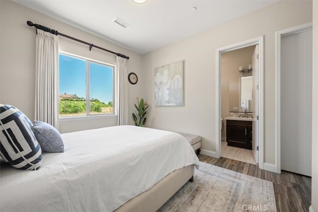 bedroom featuring hardwood / wood-style flooring and ensuite bath