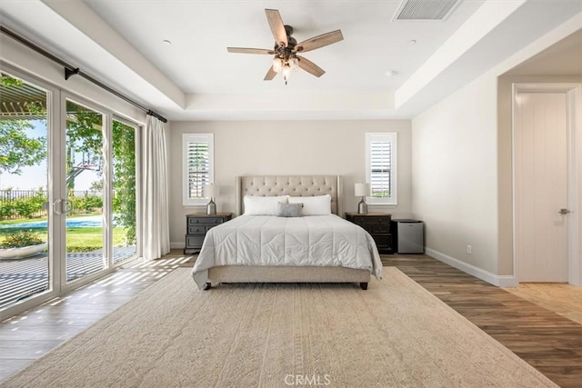 bedroom featuring a raised ceiling, ceiling fan, access to exterior, and light wood-type flooring