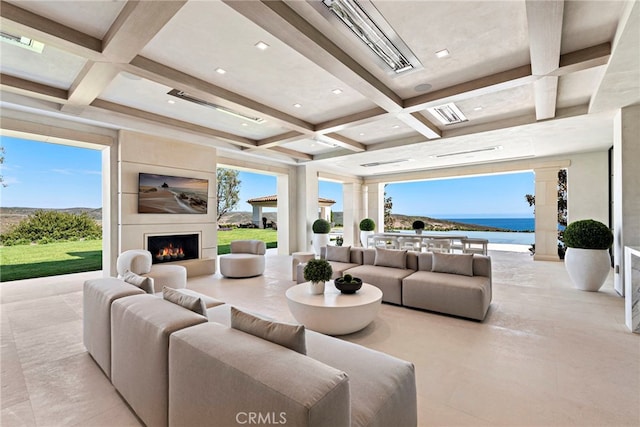 living room with a wealth of natural light, beamed ceiling, coffered ceiling, and a large fireplace