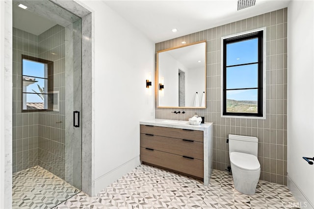 full bathroom with visible vents, toilet, a stall shower, tile walls, and vanity