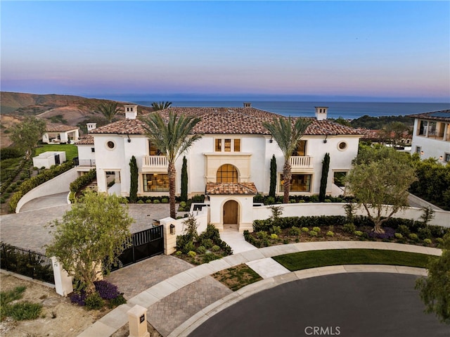 mediterranean / spanish-style home with a gate, stucco siding, a balcony, and a tiled roof