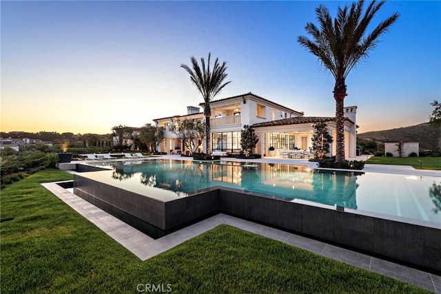 view of swimming pool featuring a yard, an infinity pool, and a patio area