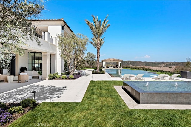 view of yard featuring a patio, a gazebo, an outdoor living space, and an infinity pool