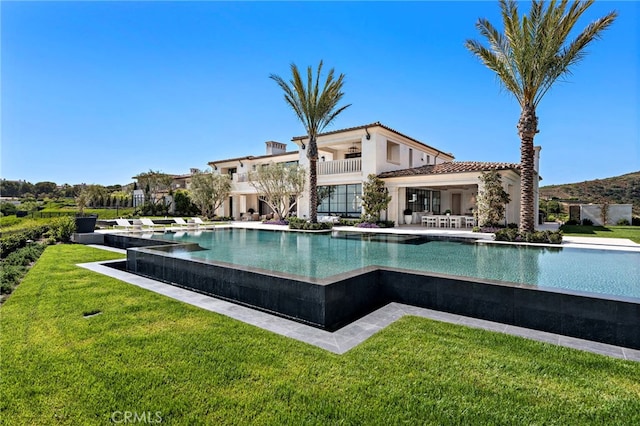 view of swimming pool featuring a lawn, an infinity pool, and a patio