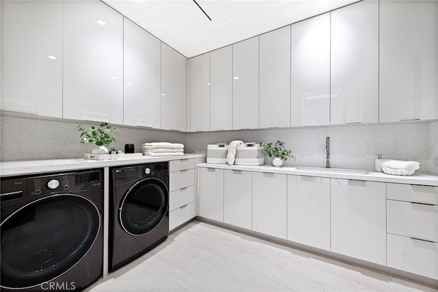 washroom with cabinet space, washing machine and dryer, and a sink