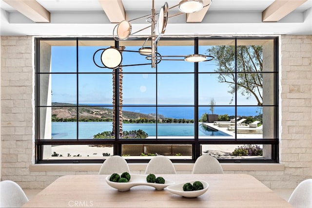 living room featuring beam ceiling, a water view, and an inviting chandelier