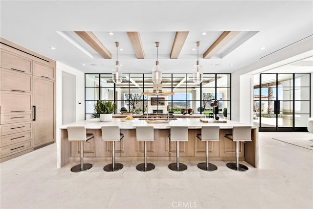 kitchen with a breakfast bar, hanging light fixtures, light tile patterned floors, and a large island with sink