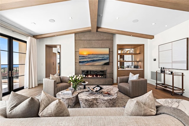 living area featuring wood finished floors, baseboards, lofted ceiling with beams, french doors, and a large fireplace