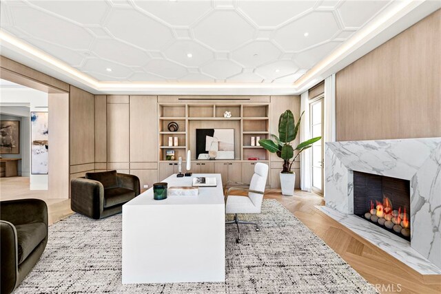 living room with built in shelves, a fireplace, and light parquet flooring