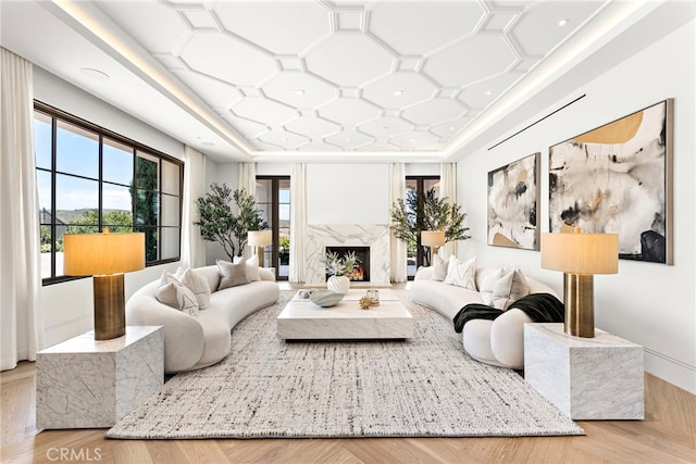 living room featuring a raised ceiling, coffered ceiling, and a premium fireplace