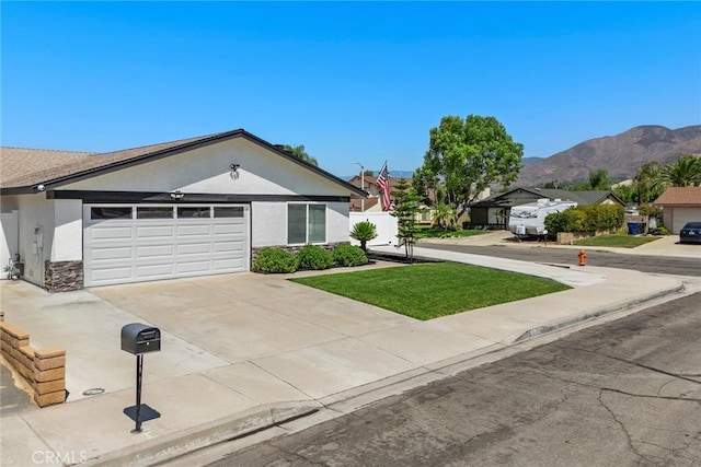 ranch-style house featuring a mountain view, a front yard, and a garage