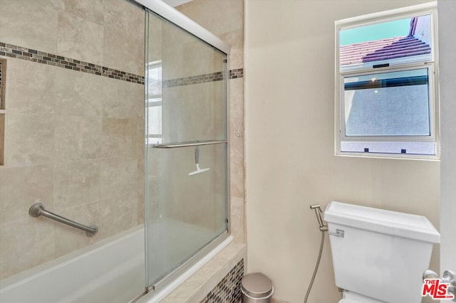 bathroom featuring bath / shower combo with glass door and toilet