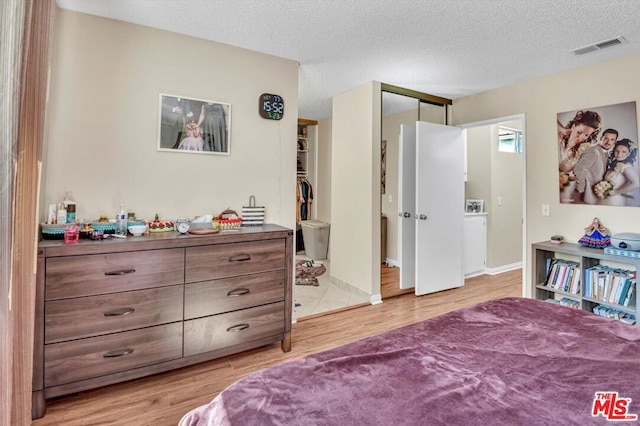 bedroom featuring light hardwood / wood-style floors, a closet, and a textured ceiling