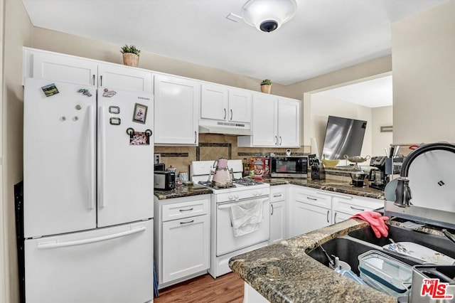 kitchen featuring white cabinetry, sink, backsplash, dark stone counters, and white appliances