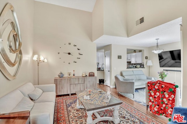 living room with hardwood / wood-style flooring and a towering ceiling