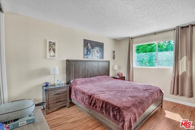 bedroom with light hardwood / wood-style floors and a textured ceiling