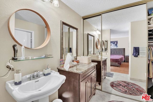 bathroom featuring tile patterned flooring, sink, and a textured ceiling