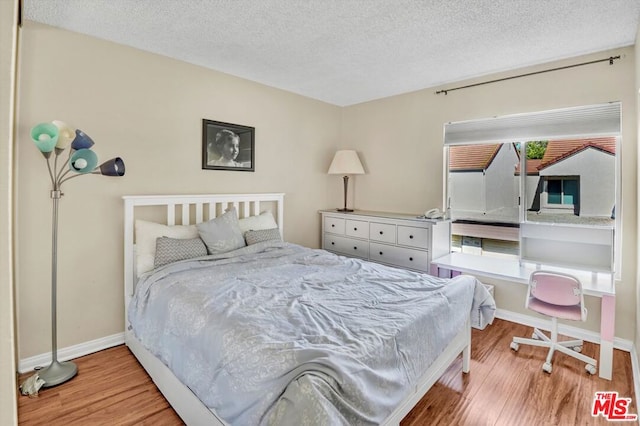 bedroom featuring multiple windows, a textured ceiling, and light hardwood / wood-style flooring