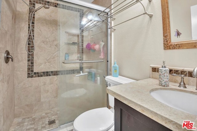 bathroom featuring vanity, toilet, and a shower with shower door