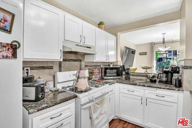 kitchen featuring white appliances, dark stone counters, decorative backsplash, and white cabinets