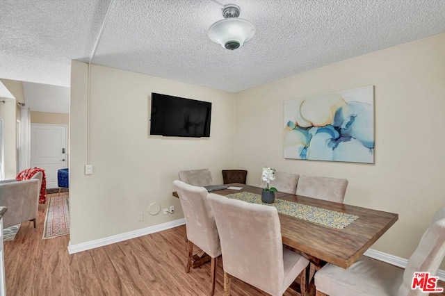 dining area with a textured ceiling and light wood-type flooring