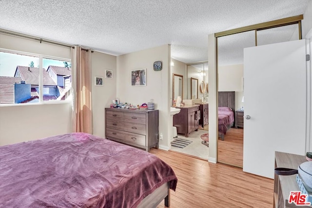 bedroom with light hardwood / wood-style floors, a closet, a textured ceiling, and ensuite bathroom