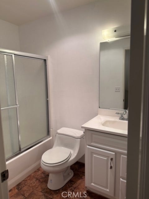 full bathroom featuring vanity, tile patterned floors, combined bath / shower with glass door, and toilet