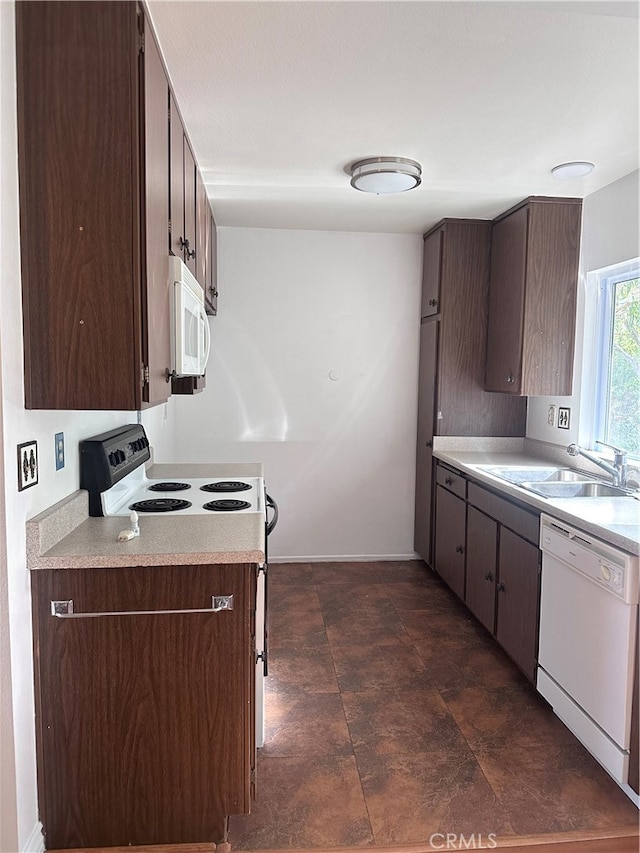 kitchen featuring dark tile patterned flooring, dark brown cabinetry, white appliances, and sink