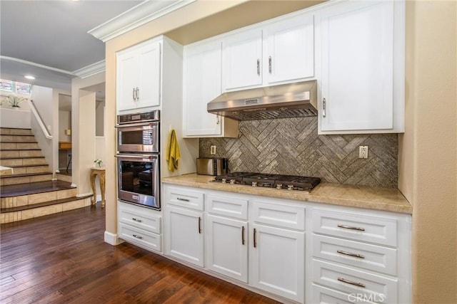 kitchen featuring dark hardwood / wood-style flooring, white cabinetry, stainless steel appliances, and extractor fan