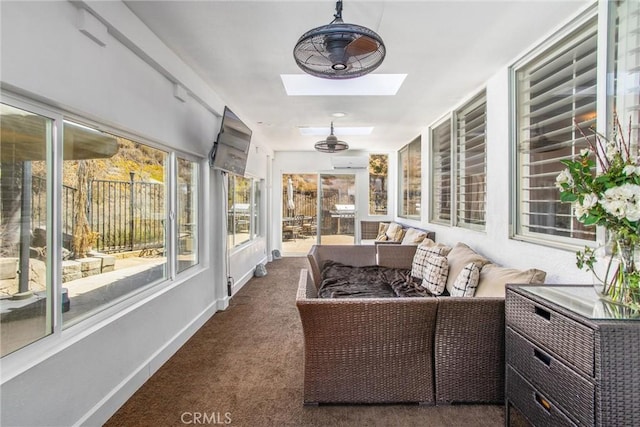 sunroom featuring ceiling fan, an AC wall unit, and a skylight