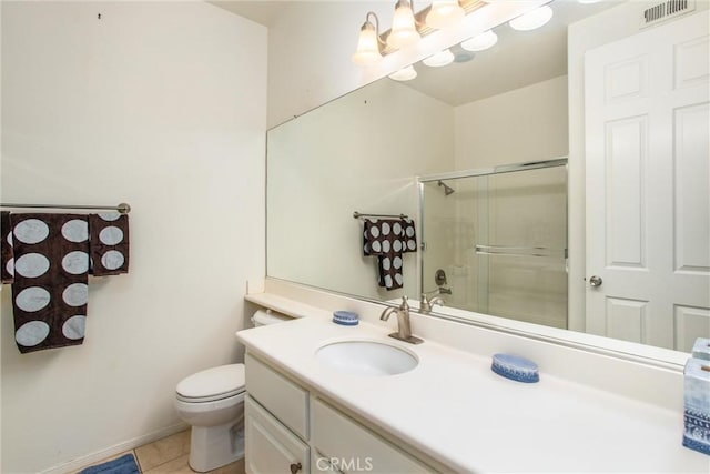 bathroom with tile patterned floors, a shower with door, vanity, and toilet