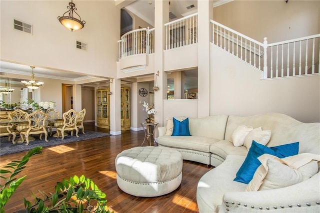 living room featuring dark hardwood / wood-style flooring, crown molding, a high ceiling, and an inviting chandelier