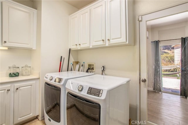 washroom with cabinets, washing machine and clothes dryer, and light hardwood / wood-style flooring