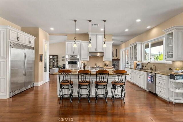 kitchen with white cabinets, appliances with stainless steel finishes, a center island, and decorative light fixtures