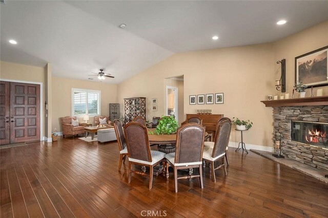 dining area with a fireplace, dark hardwood / wood-style flooring, vaulted ceiling, and ceiling fan