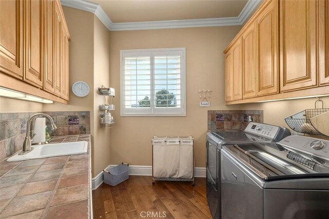 washroom with sink, cabinets, separate washer and dryer, ornamental molding, and hardwood / wood-style flooring